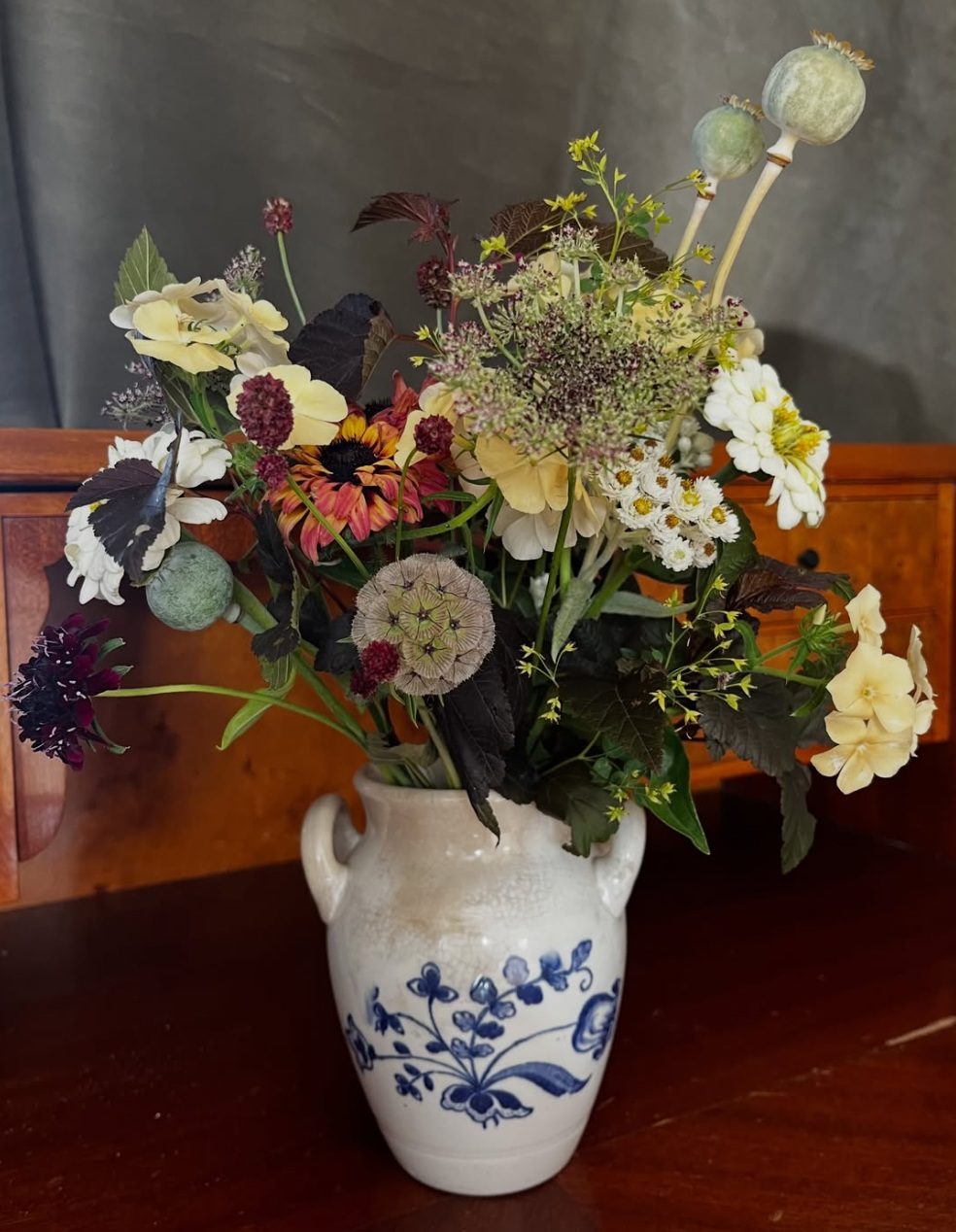 Färgstark sommarbukett i en gammal blåmönstrad lerkruka, med vallmokapslar och rudbeckia.